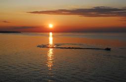 Sunset over a glass smooth Lake Erie with a pleasure boat moving through the sun's reflection