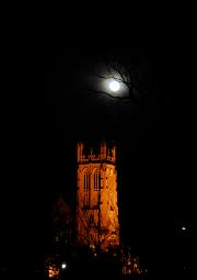 full moon over church steeple through tree branches