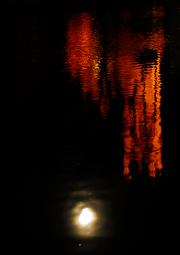 full moon and lighted church steeple reflected in water