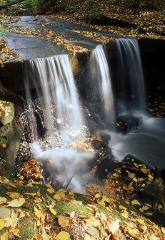 Waterfall in Cleveland, Ohio's metroparks with yellow fall leaves on the ground